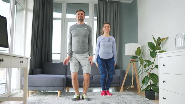 Caucasian Couple is Doing Jumping Jacks Exercise at Home in Cozy Bright Room Slow Motion