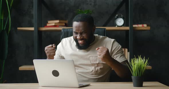 Excited African Businessman Winner with Laptop at Workplace