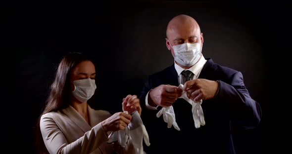 Portrait of a Couple in Business Clothes on a Black Background. They Put Disposable Masks on Their