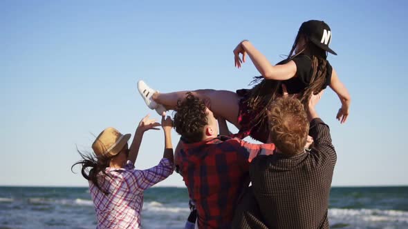 Large Group of Young People Lifting Their Female Friend Up in the Air and Throwing Her Up on Raised