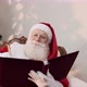 Santa Claus writing in a red cover book. Jotting down names or gifts for Christmas - VideoHive Item for Sale