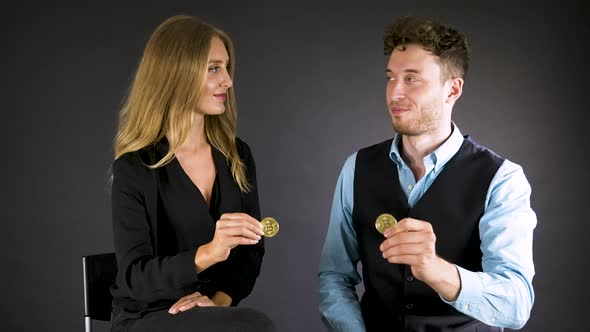 Sitting business couple exchange looks and shows cryptocurrency coins.