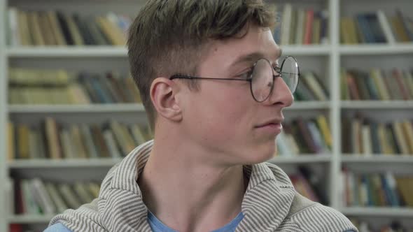 Handsome Smiling Smart Guy in Glasses Looking at Camera in the Library