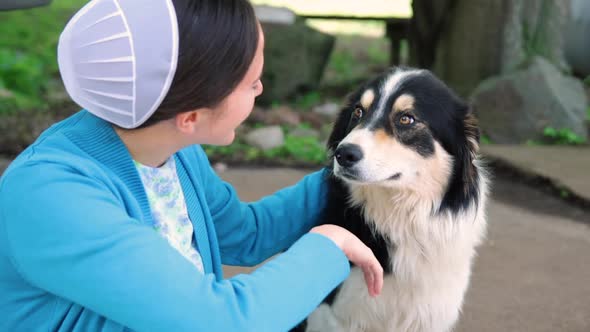A young Mennonite woman petting her dog in slow motion.