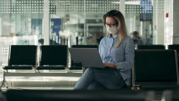 Gorgeous Woman in a Safety Mask Is Working on a Laptop