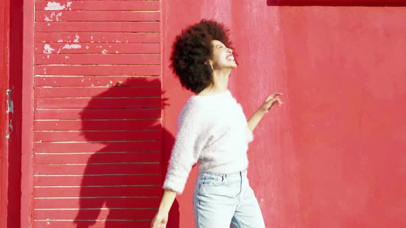 Young woman dancing happily in front of red wall