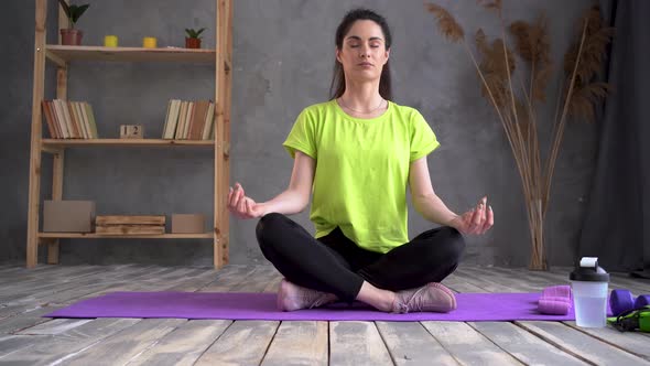 Healthy Beautiful Woman in Sports Top and Leggings Practicing Yoga at Home Sitting in Lotus Position