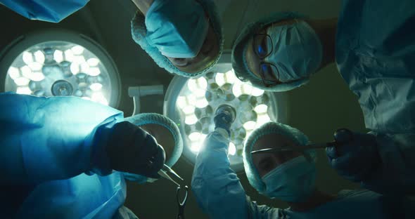 Surgeons wearing face masks holding surgical instruments in operating theatre