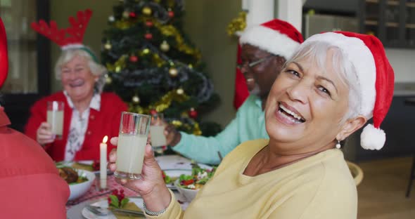 Happy mixed race senior woman celebrating meal with friends at christmas time