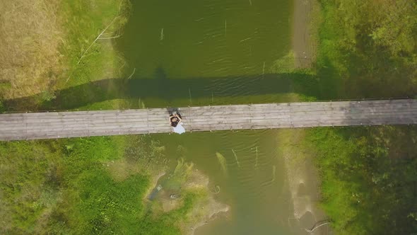 Camera Turns Above Newly Wedded Couple on Old Wooden Bridge
