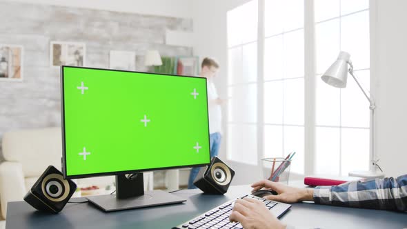 Zoom Out Footage of Male Typing on Keyboard of a Green Screen PC Display