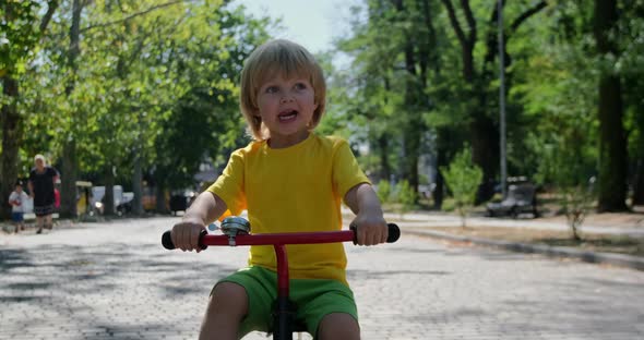 Happy boy rides a bike in the park.