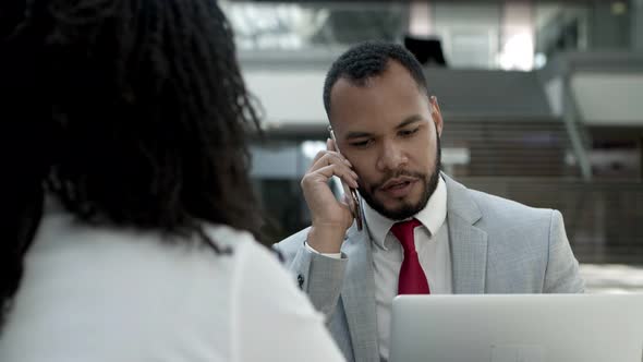 Thoughtful Young Businessman Talking on Smartphone 