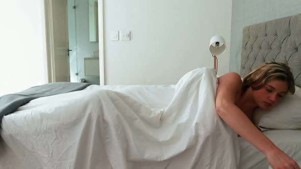 Young woman waking up in bed and stretching his arms