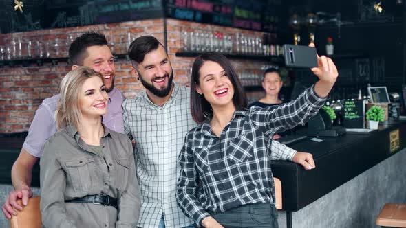 Laughing Young Man and Woman Taking Selfie Using Smartphone Having Fun at Restaurant