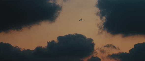 Plane flying into the clouds at sunset, slow motion 4K