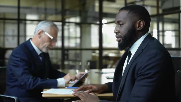 Mature Business Man Refusing African Job Candidate Reading Resume on Tablet