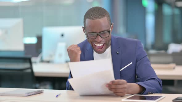 African Businessman Celebrating Success While Reading Documents