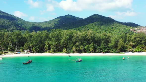 Fishing boats anchoring on calm clear water of shallow turquoise lagoon near white sandy beach of tr