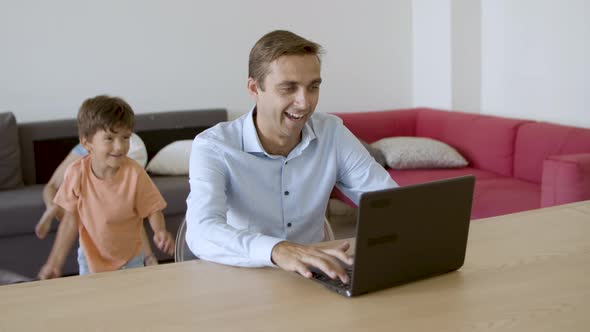 Cheerful Father Looking at Laptop Screen