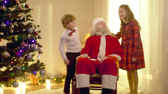 Positive Santa Clause Boy and Girl Looking at Camera Waving Smiling Posing Indoors