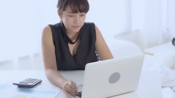 Businesswoman working calculate expenses and typing laptop computer on desk with saving finance.