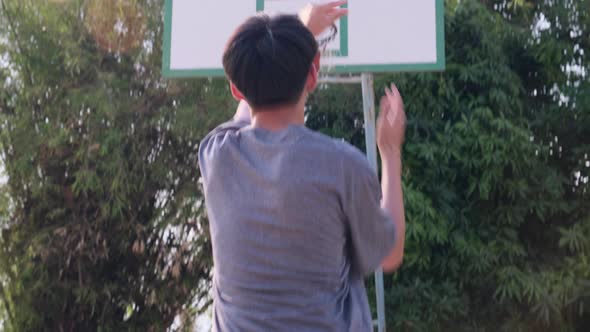 Young sports men practicing basketball on the outdoor court.