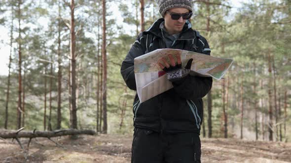 Orienteering in the forest. Tourist on a hike in a forest park with a map.