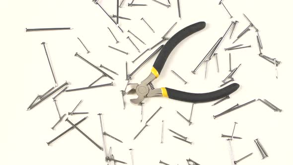 Wire Cutters with Yellow, Gray Handle on White Among Nails, Rotation, From Above