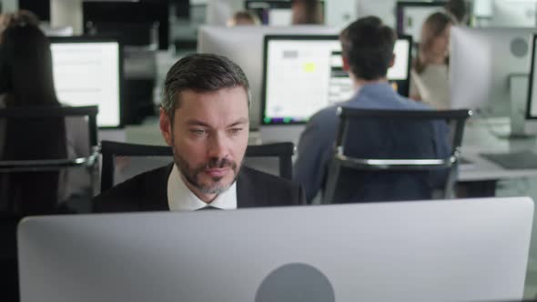 Portrait of MiddleAged Man in Open Space Office Working on Decktop Computer