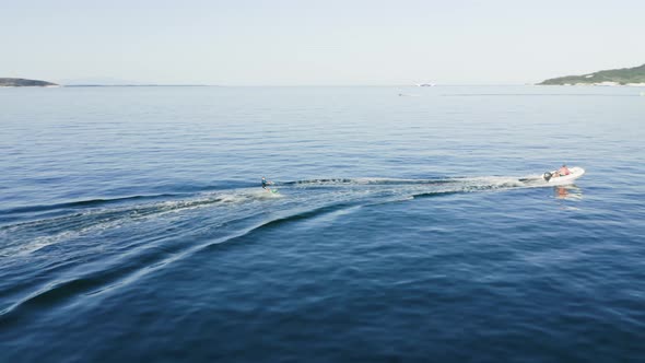 Drone view of kid doing water ski in the sea.