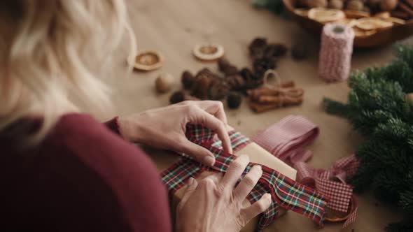 Blonde woman packing Christmas present. Shot with RED helium camera in 8K