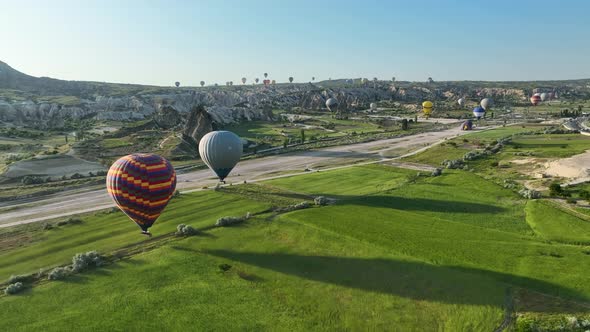 Hot air balloons fly over the mountainous landscape of Cappadocia, Turkey.