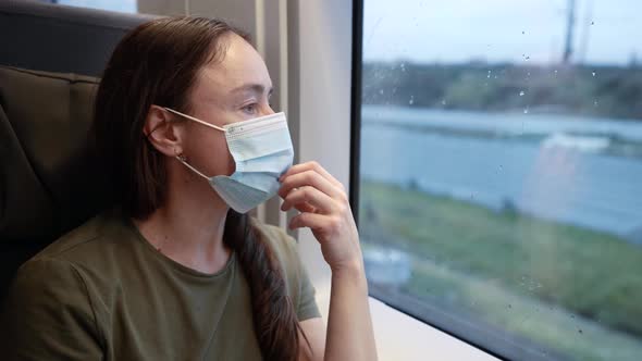 Closeup Portrait of an Adult Thoughtful Woman in a Medical Mask in a Transport Train