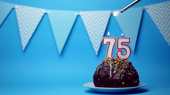 chocolate birthday cake with a burning candle number seventy five, 75 on a blue background. Copy spa