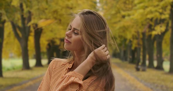 Close-up Portrait of Cute Caucasian Girl Standing in Autumn Park and Sighing