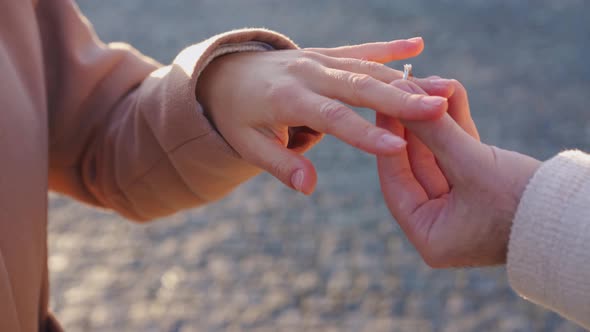 Male hands putting a ring on his woman finger