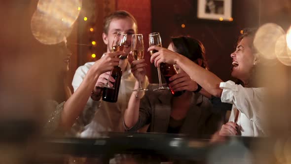 Young People Are Celebrating Something in Cafe. They Are Clinking Glasses with Beer and Cocktails