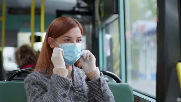 Woman Follows Modern Precautions and Wears a Medical Mask and Gloves While Traveling on Public Bus