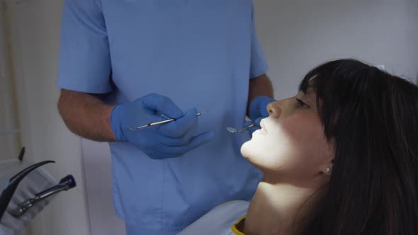 Caucasian male dentist examining teeth of female patient at modern dental clinic