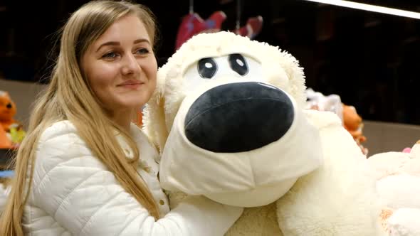 A Young Woman Plays with a Fluffy Toy of a White Dog Looks at the Camera