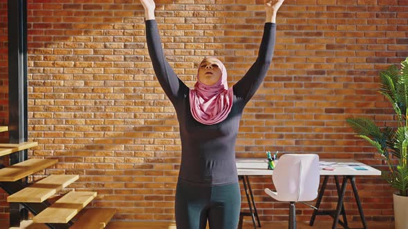 Young Arab Woman in Pink Hijab and Sports Leggings Doing Breathing Exercises