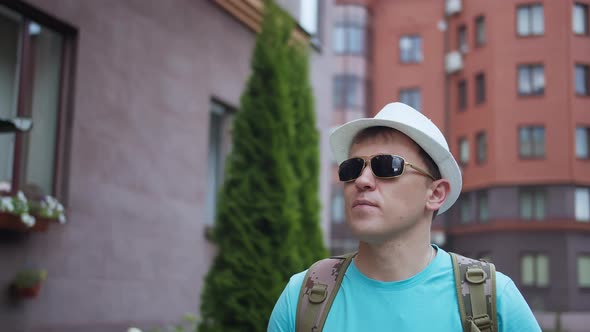 Man Tourist Walks Around the City Wearing a Hat and Sunglasses Camera Tracking