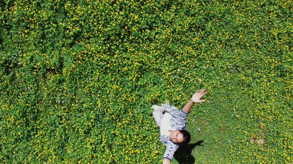 Alone Girl Is Standing in Sunny Blooming Meadows, Camera Is Flying Up Over Her