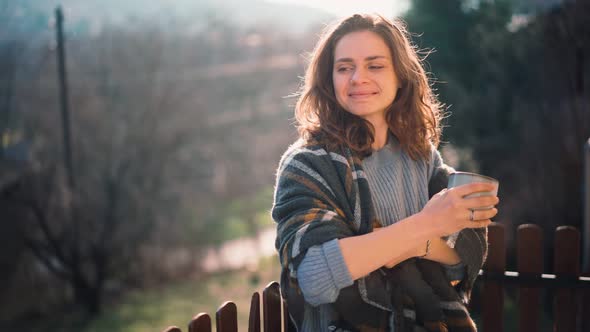 A Young Woman Enjoying Her Morning Coffee While Standing on a Balcony