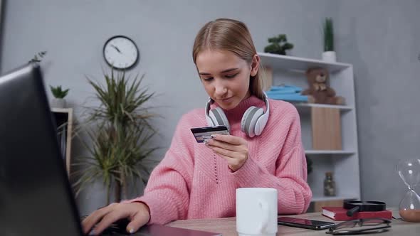 Modern Young Woman in Stylish Sweater Sitting Near Computer and Using Credit Card