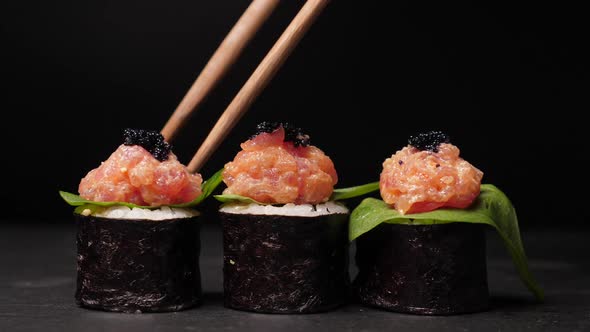 Take One Sushi Roll From Black Slate Board Using Chopsticks