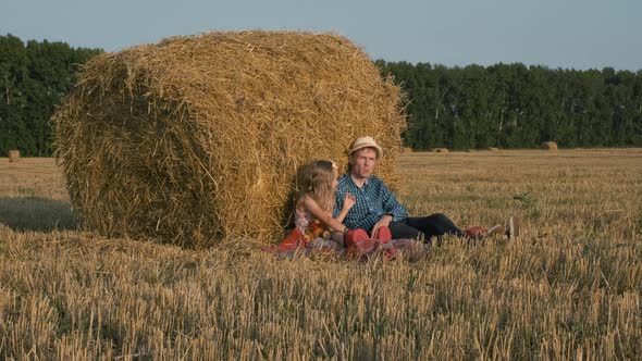 Father with Daughter Relaxing Near Hay Bale