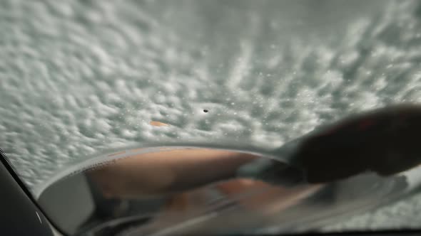 Closeup Windshield with White Foam and Female Hand Rubbing Glass Cleaning Vehicle