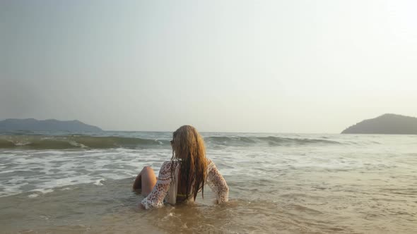 Woman in a White Tunic on the Beach Near the Sea